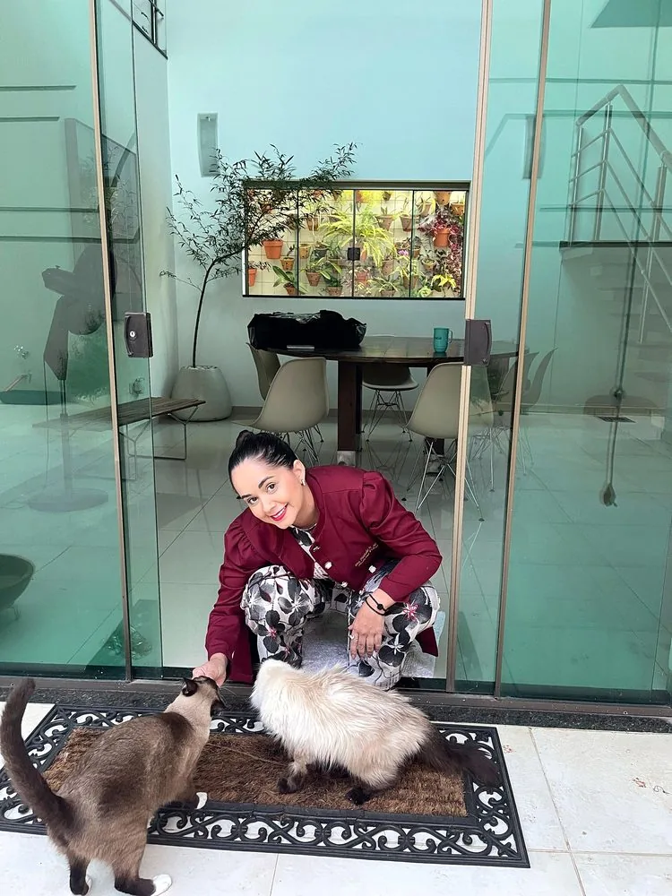 Dra. Nathalia acariciando dois gatos na recepção da clínica
