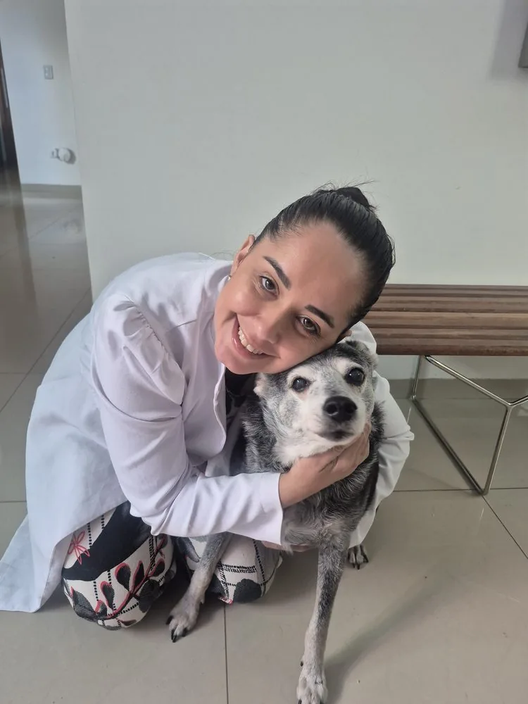 Dra. Nathalia abraçando um cão idoso na clínica